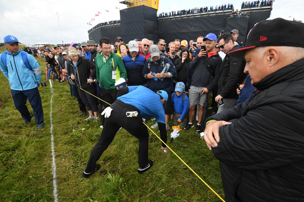 PORTRUSH Rory McIlroy raccoglie la pallina fuori limite sulla buca 1 (Foto di Glyn KIRK / AFP).